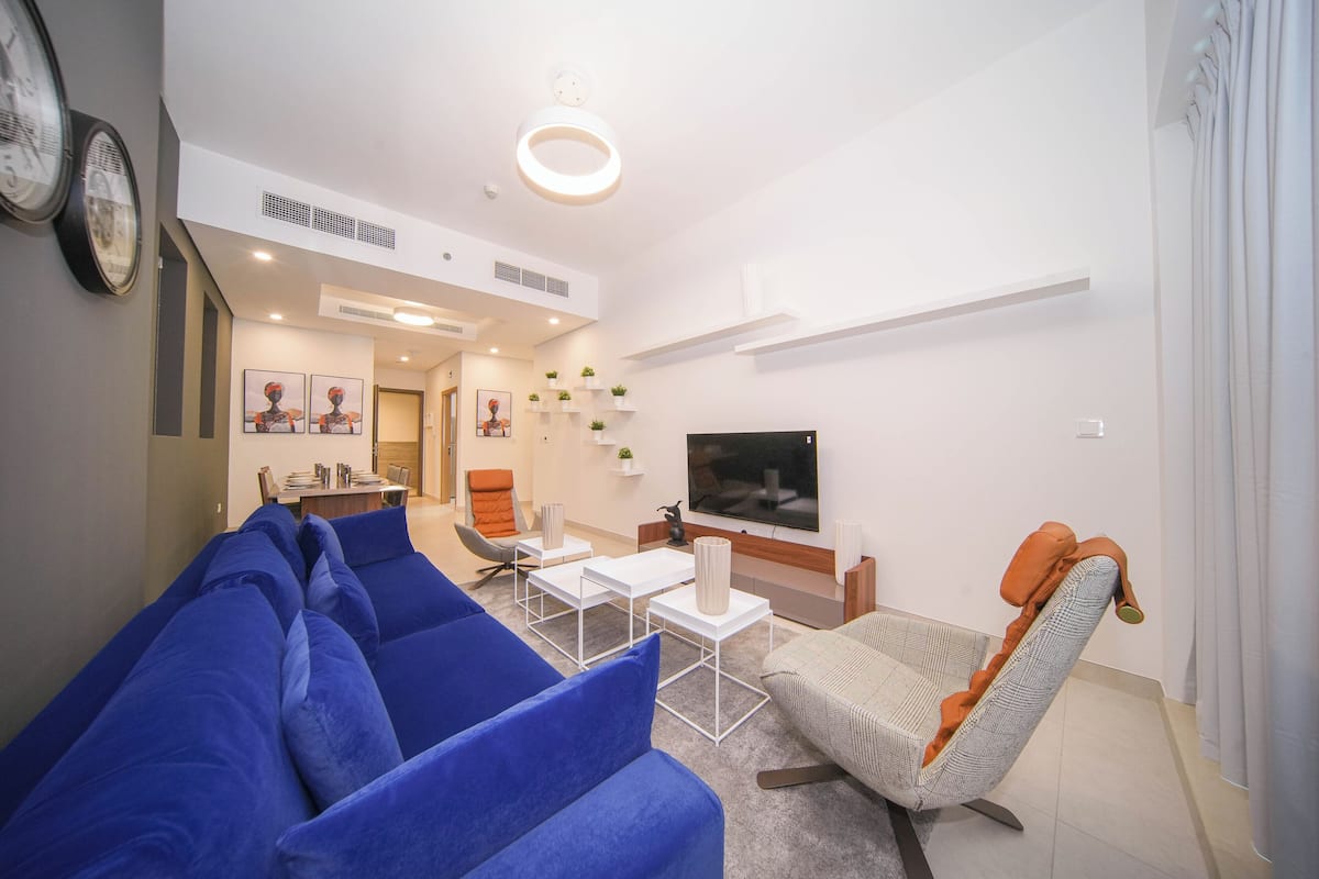 Ein modernes Wohnzimmer mit einem blauen Sofa, einem Relaxsessel, einem Couchtisch und einem Flachbildfernseher.