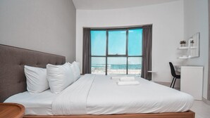 Une chambre d’hôtel moderne avec un grand lit, un bureau et une vue sur la plage.