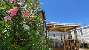 A wooden deck with outdoor furniture, a covered patio area, and a house in the background.