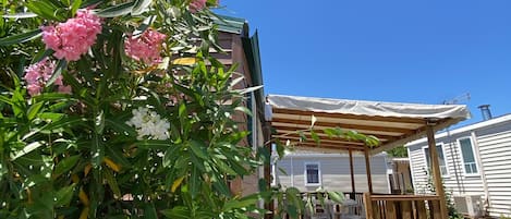 A wooden deck with outdoor furniture, a covered patio area, and a house in the background.