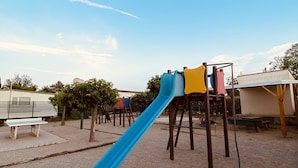 A playground with a blue slide, benches, and a fenced area.