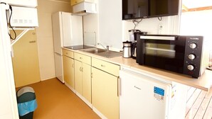 A compact kitchen with white cabinets, a microwave, a coffee maker, and a refrigerator.