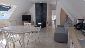 Een moderne keuken met een inbouwfornuis, een koffiezetapparaat en een eethoek met een ronde tafel en stoelen.