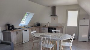 Een moderne keuken met een eethoek, voorzien van een dakraam, een ingebouwde magnetron en een koelkast.