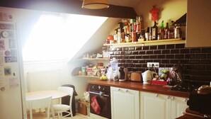A kitchen with white cabinets, a wooden countertop, and a window providing natural light. - Appartement 100m2 Dernier Étage Calme et Lumineux (Melun)