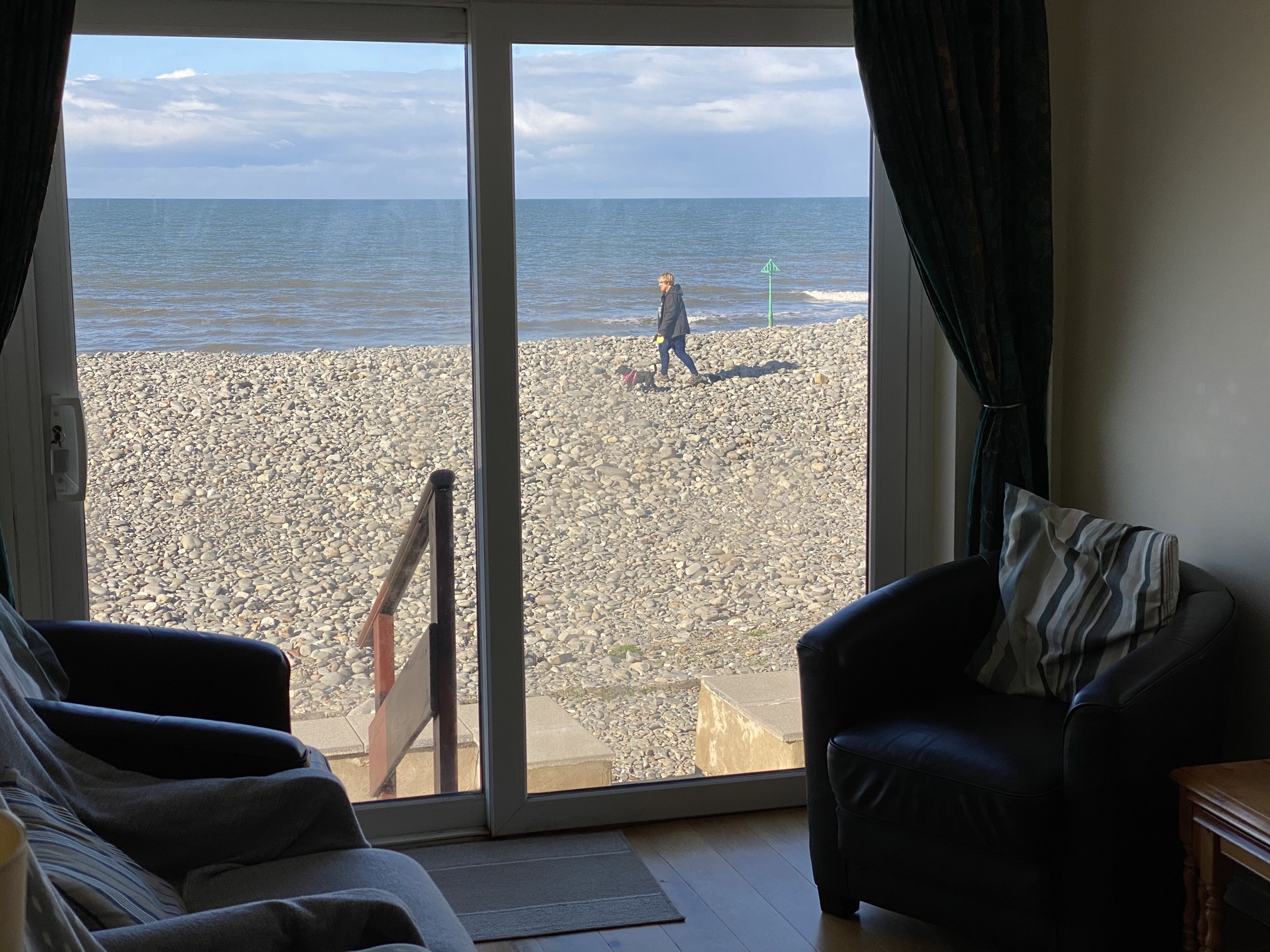 A room with a large sliding glass door leading to a pebble beach.