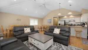 A spacious living area with a dining set, two sofas, a coffee table, and a kitchen in the background. - Oceanside 7BR House with Private Pool and Hot Tub (Corolla)
