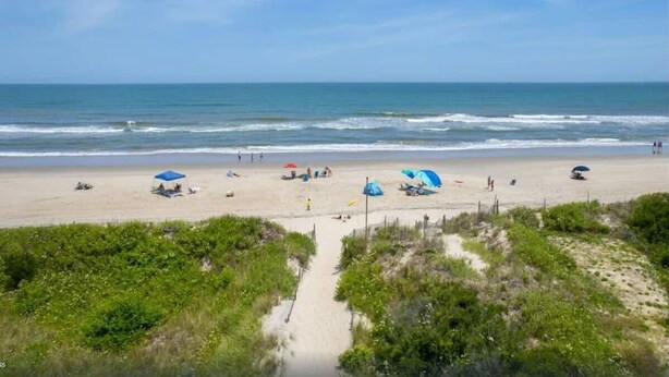 A beach with umbrellas and people. - Oceanside 7BR House with Private Pool and Hot Tub (Corolla)