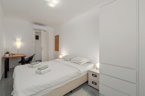 Cozy retreat with a neatly made bed, bedside table, and desk, perfect for a restful stay.
