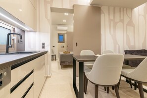 A modern kitchen with a built-in sink, a dining area with a table and chairs, and a small seating area with a sofa.