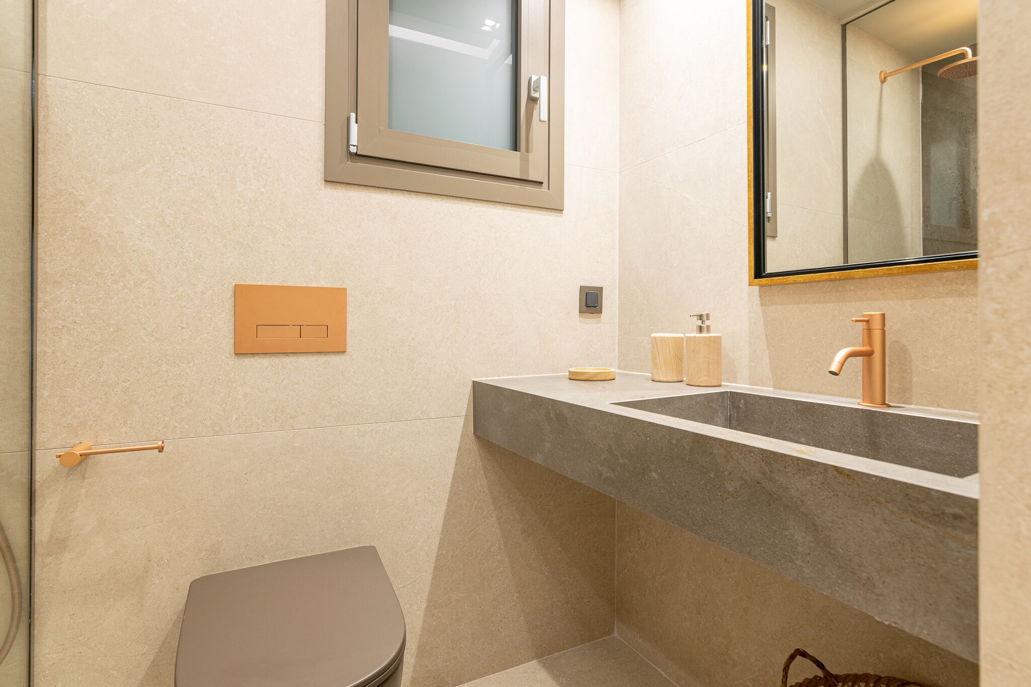 A modern bathroom with a grey sink, a mirror, and a toilet.