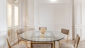 Een kamer met een glazen ronde tafel, vier stoelen, een grote spiegel en een decor kast.