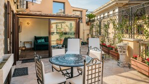 Une terrasse avec une table ronde et des chaises, un canapé et une porte vitrée donnant sur un espace intérieur.