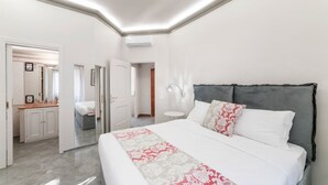 A modern bedroom with a large bed, a bedside table, a mirror, and a walk-in closet.