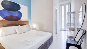 Una habitación de hotel moderna con una cama grande, un cabecero, una obra de arte en la pared, un espejo y una silla.
