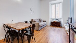 Una sala de estar moderna con una mesa de comedor de madera, sillas negras, un sofá gris y un aparador de madera.