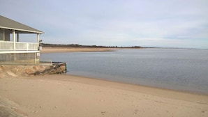 En strand med en bygning, der har balkon og en stenvæg.
