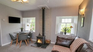 Ein gemütliches Wohnzimmer mit Kamin, Ledersofa, Esstisch und Stühlen.