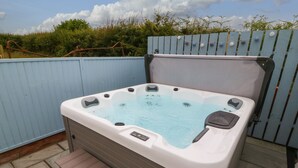 Un jacuzzi con un banco de madera y un escalón para acceder, rodeado por una cerca azul.
