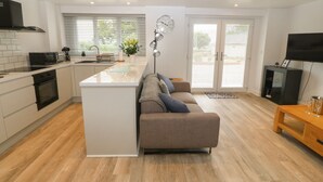 Una cocina moderna con una isla central, un área de comedor con sofá y televisión.