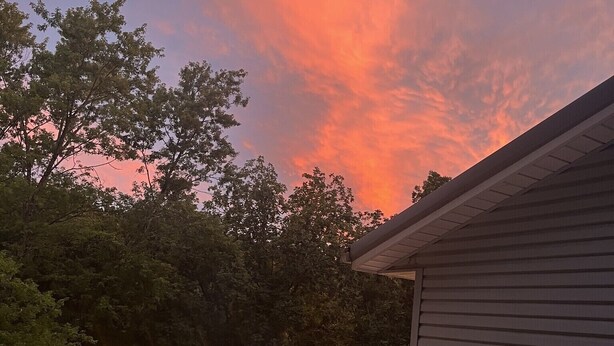 Un jacuzzi en una terraza con un atardecer de fondo.