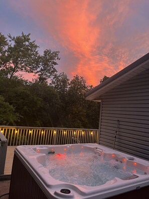 Un jacuzzi en una terraza con un atardecer de fondo.