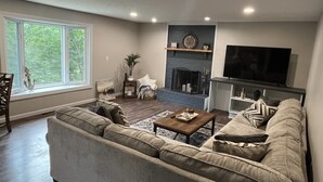 Una sala de estar con chimenea, televisor y un ventanal grande.