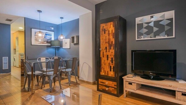 Un salon moderne comprenant un coin repas, un téléviseur et un panneau mural en bois au design original.
