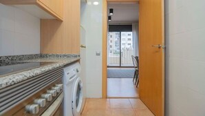 A compact kitchen with a washing machine, a built-in oven, and a countertop. - Eixample 2 bedroom with private terrace (Barcelona)