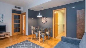 A modern living room with a glass dining table, a blue sofa, and a patterned rug. - Eixample 2 bedroom with private terrace (Barcelona)
