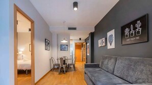 Una sala moderna con un sofá gris, piso de madera y un comedor con mesa y sillas.