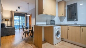 Una cocina funcional con armarios de madera, lavadora y microondas.