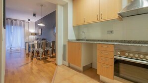 Eine moderne Küche mit Holzschränken, einem Edelstahlbackofen und einem Essbereich mit Tisch und Stühlen.