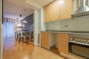 Une cuisine moderne avec des meubles en bois, un four en acier inoxydable et un coin repas comprenant une table et des chaises.