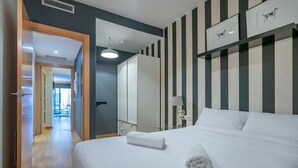 Ein Hotelzimmer mit einem großen Bett, einem Nachttisch, einer Lampe und Blick auf den Flur.