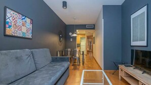 Ein modernes Wohnzimmer mit grauem Sofa, einem Couchtisch und einer TV-Konsole.