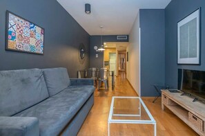 Un salon moderne avec un canapé gris, une table basse et un meuble pour la télévision.