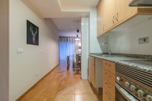A kitchen with wooden cabinets, a granite countertop, and a built-in oven. - Heart of Eixample 2BD with balcony (Barcelona)