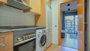 Eine kompakte Küche mit Einbauofen, Waschmaschine und Kühlschrank.