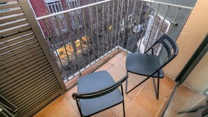 Un balcon avec deux chaises noires et une rambarde en métal.