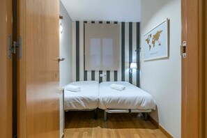 A room with two beds, a striped wall, a world map, and a lamp.