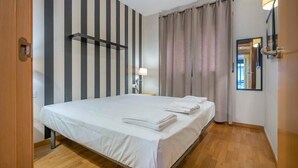 Une chambre d’hôtel avec un lit, une table de chevet, une lampe, un miroir et un rideau.