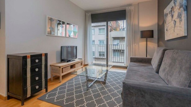 Un salon moderne avec un canapé, un téléviseur, un meuble et une table en verre.