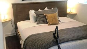 Un dormitorio con cama, almohadas, cabecera, mesita de noche y lámpara.