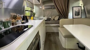 A compact RV kitchen with a sink, stove, and a small dining area.