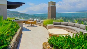 A rooftop terrace with a curved sofa, a round coffee table, and a dining area with chairs and a table. - Reserva Del Mar 624 (Santa Marta)