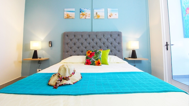 A hotel room with a large bed, two bedside lamps, a blue wall, and a window. - Reserva Del Mar 624 (Santa Marta)
