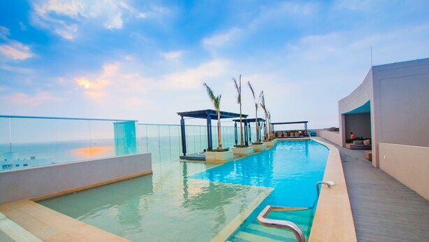 A rooftop infinity pool with clear views of the ocean, a covered seating area, and a wooden deck. - Reserva Del Mar 624 (Santa Marta)