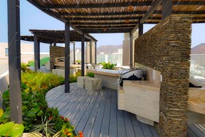 An outdoor patio with a stone wall, wooden deck, and outdoor seating area. - Reserva Del Mar 624 (Santa Marta)
