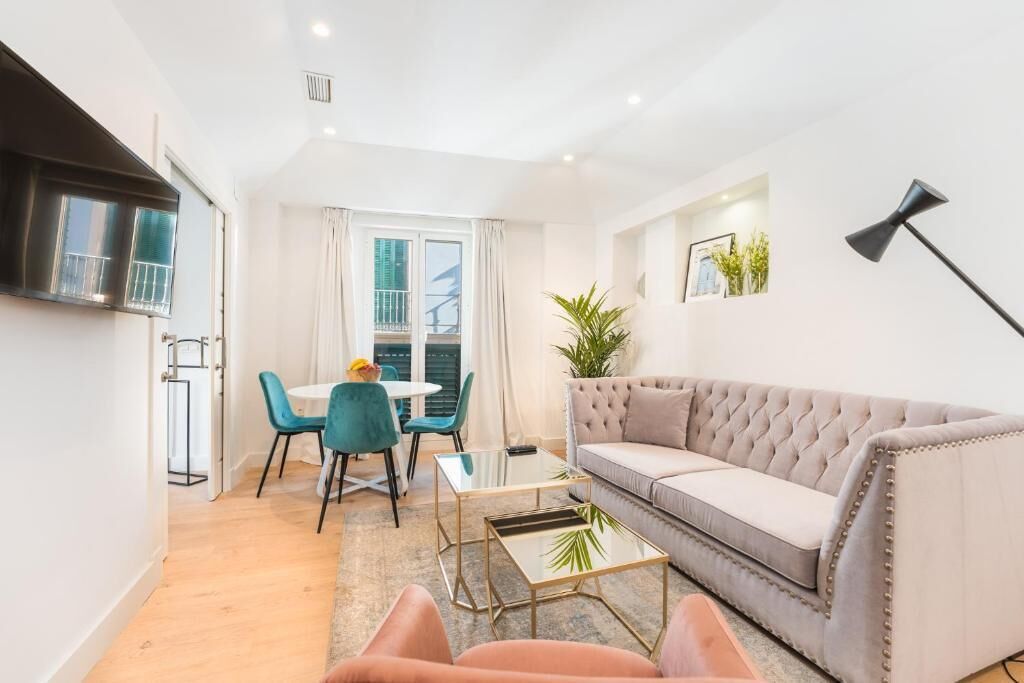 A modern living room with a sofa, a coffee table, and a dining area with chairs and a table.